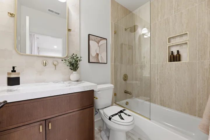 Bathroom featuring a dark wood-finish vanity with a light-toned countertop, a wall-mounted faucet, and a rectangular mirror