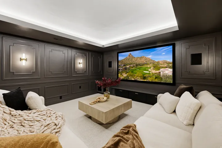 Integrated media screen, recessed ceiling lighting, wall paneling, built-in lower cabinetry, and wall-mounted sconce lighting