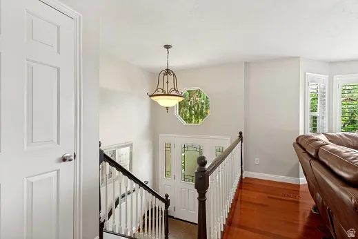 Entry and stairs, Brazilian Cherry hardwood flooring, decorative spindle balusters, pendant light fixture, octagonal window, and bay windows with plantation shutters