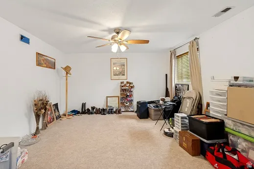 Large basement bedroom featuring a ceiling fan, white walls, and window with blinds
