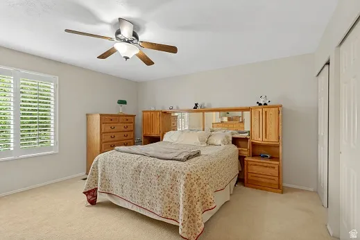 Primary Bedroom, Ceiling fan with integrated lighting, window with white plantation shutters, neutral wall color, carpet