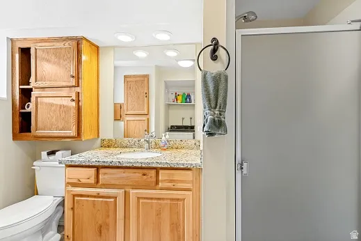 Bathroom vanity with cherry wood cabinetry, a granite countertop, and a white undermount sink