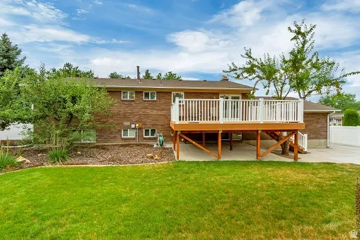 Exterior featuring a red brick facade, composite wood-finish deck with white railings, and a green lawn