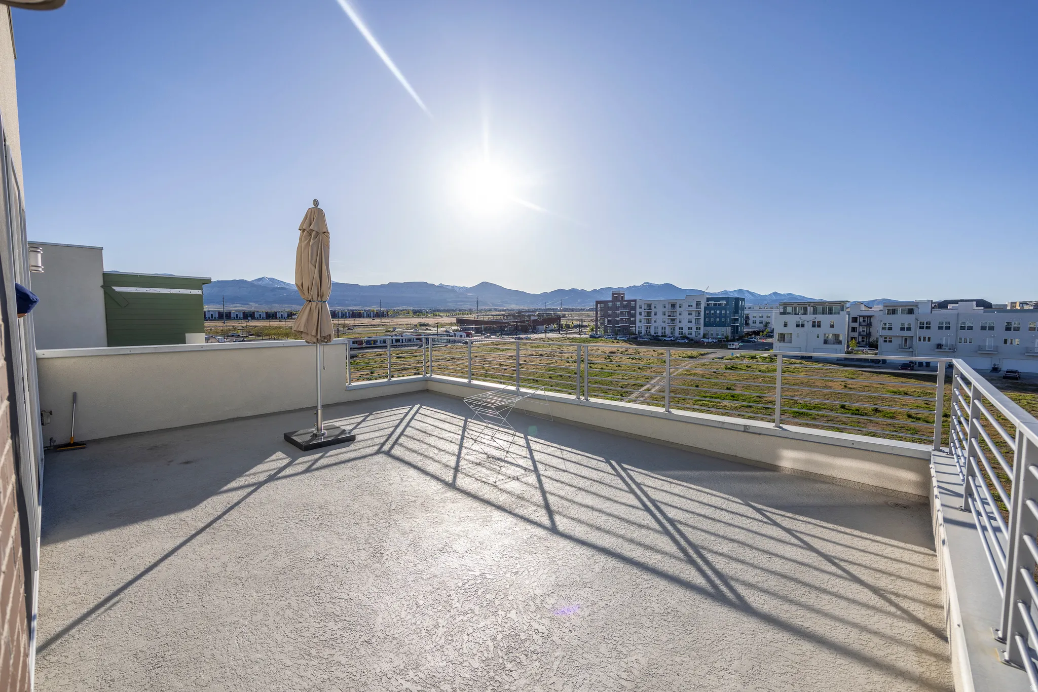 Expansive rooftop patio featuring a concrete surface, white perimeter wall, and metal railings