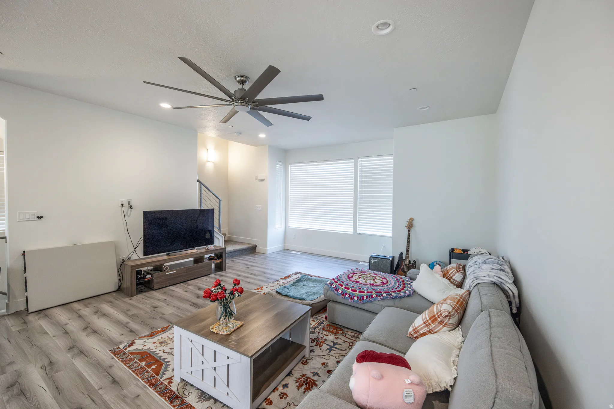 Spacious living area featuring wood-finish flooring, recessed lighting, and a modern ceiling fan