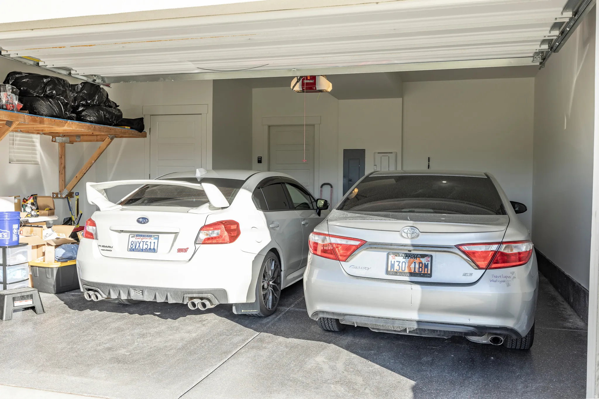 Spacious two-car garage with epoxy-coated flooring, overhead storage shelving, and integrated lighting