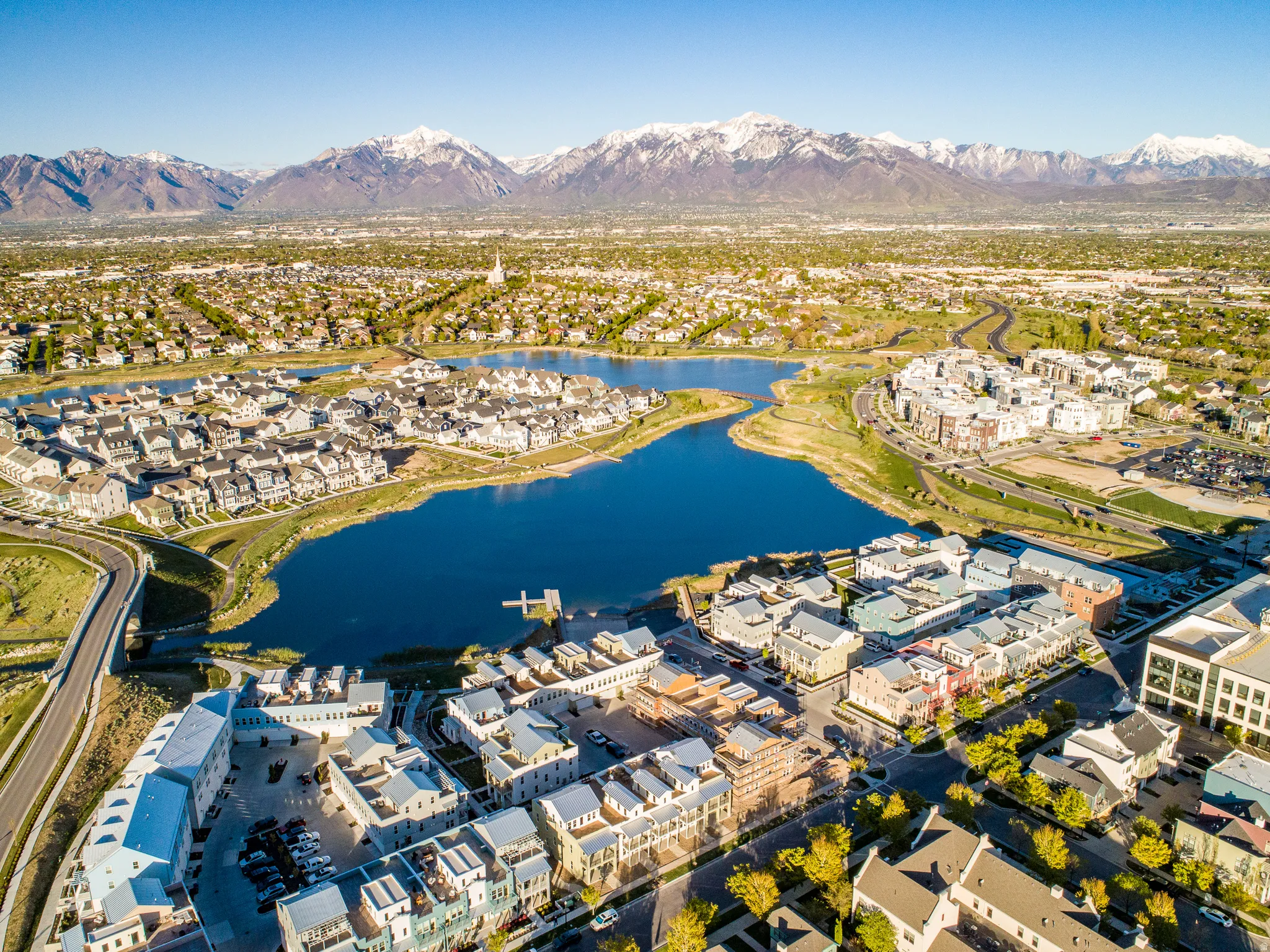 Aerial perspective highlighting a residential community, a prominent lake, and snow-capped mountains in the background