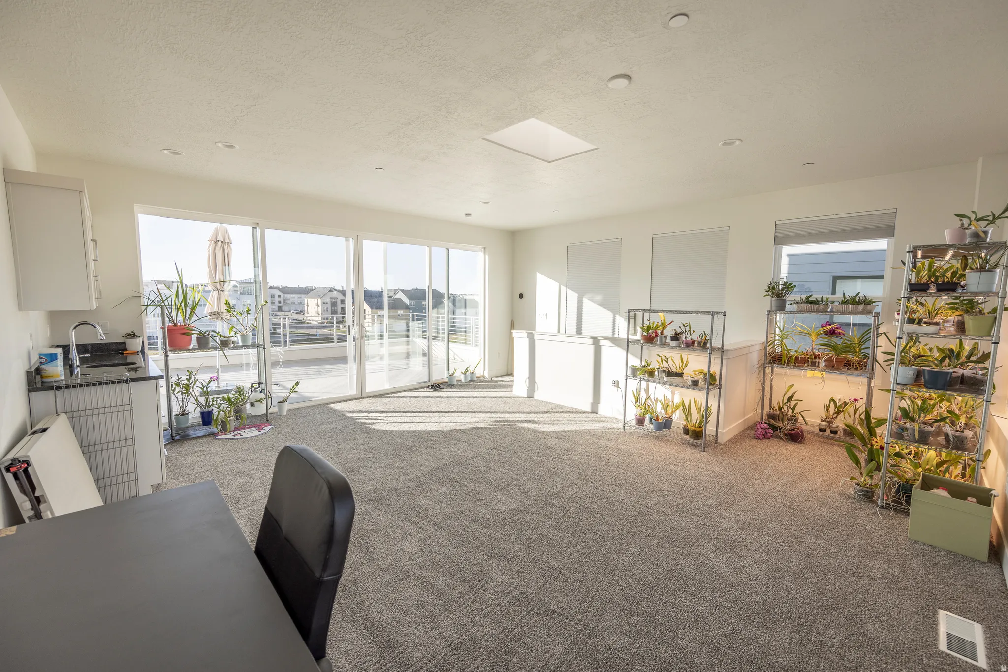 Sliding glass doors leading to an outdoor terrace, recessed lighting, skylight, and built-in wet bar with sink