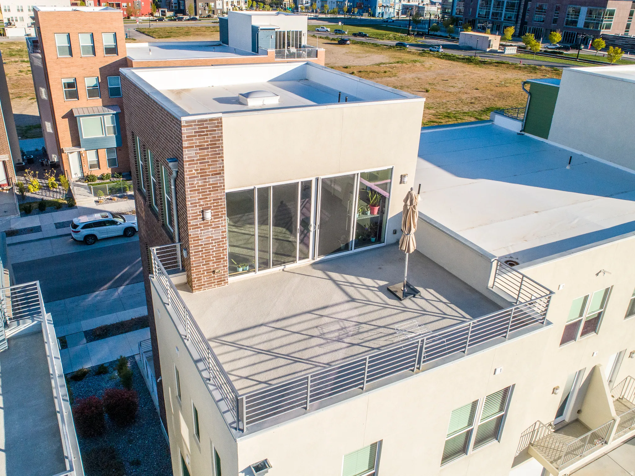 Rooftop deck featuring a horizontal bar railing, large sliding glass doors, and a brick-finish exterior accent