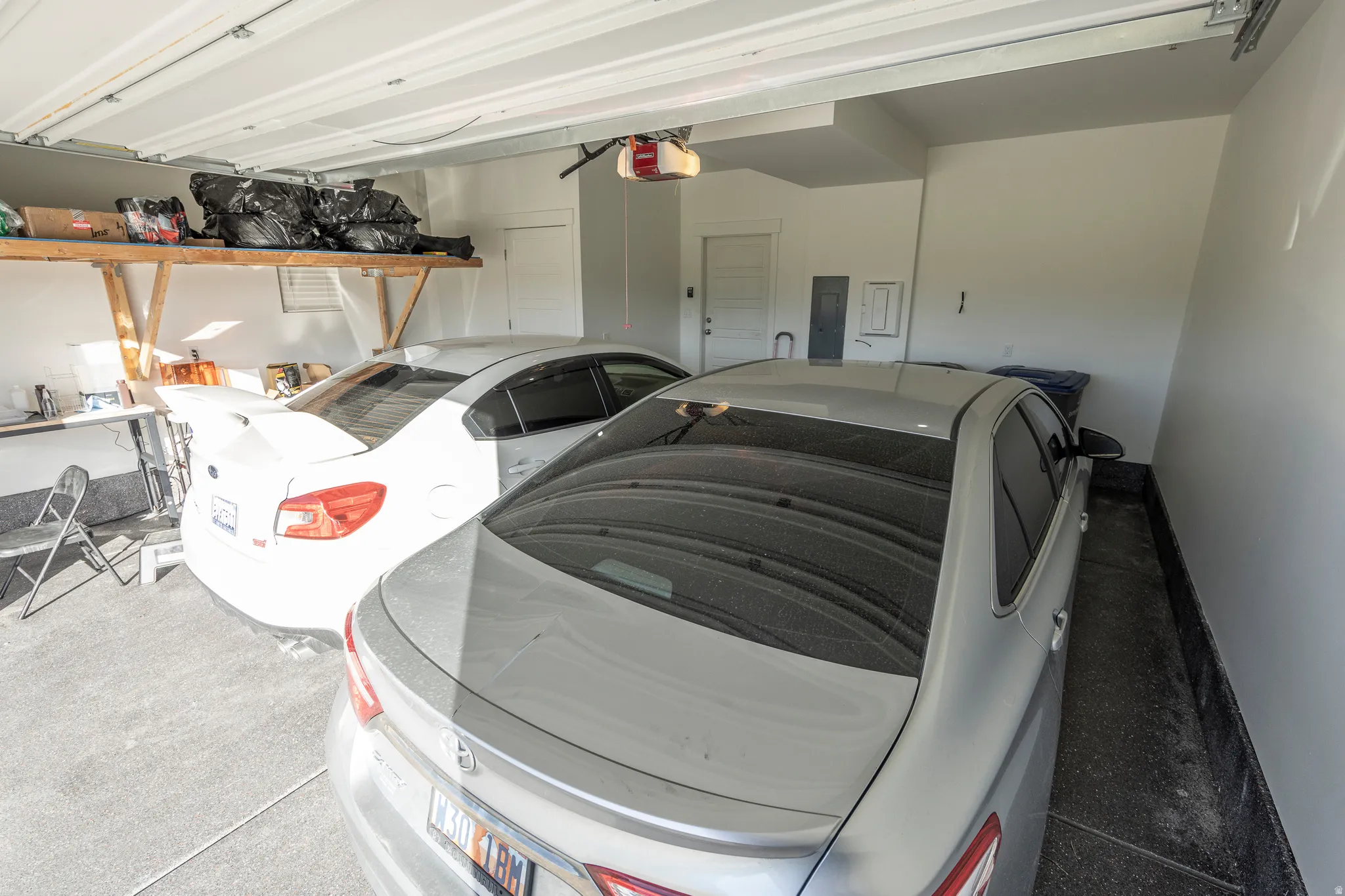 Two-car garage featuring painted walls, concrete flooring, and built-in overhead shelving