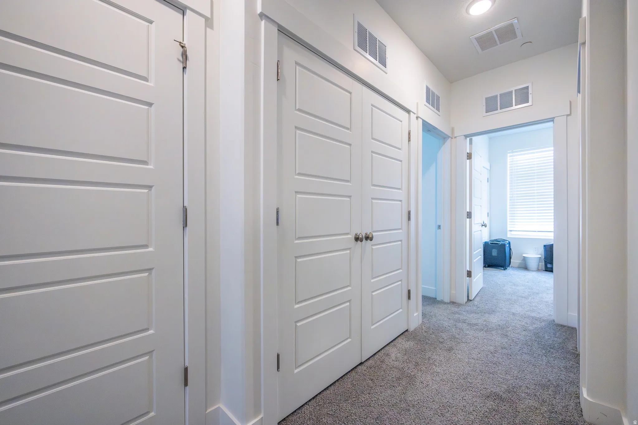 Hallway featuring light gray carpet flooring, recessed lighting, and white paneled doors with brushed nickel hardware