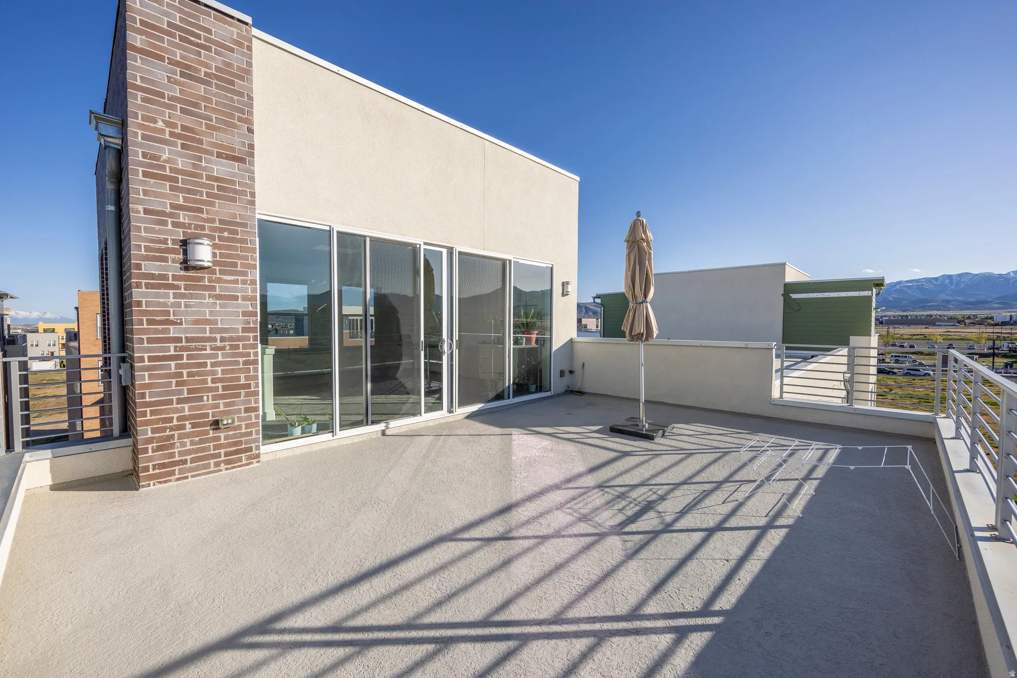 Expansive outdoor deck featuring a textured surface, contemporary metal railings, and wide sliding glass doors