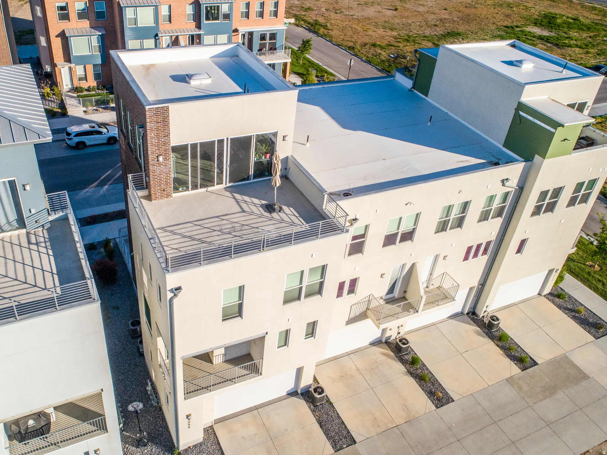 Modern architecture featuring a flat roofline, multiple balconies with railings, attached garages, and a rooftop terrace