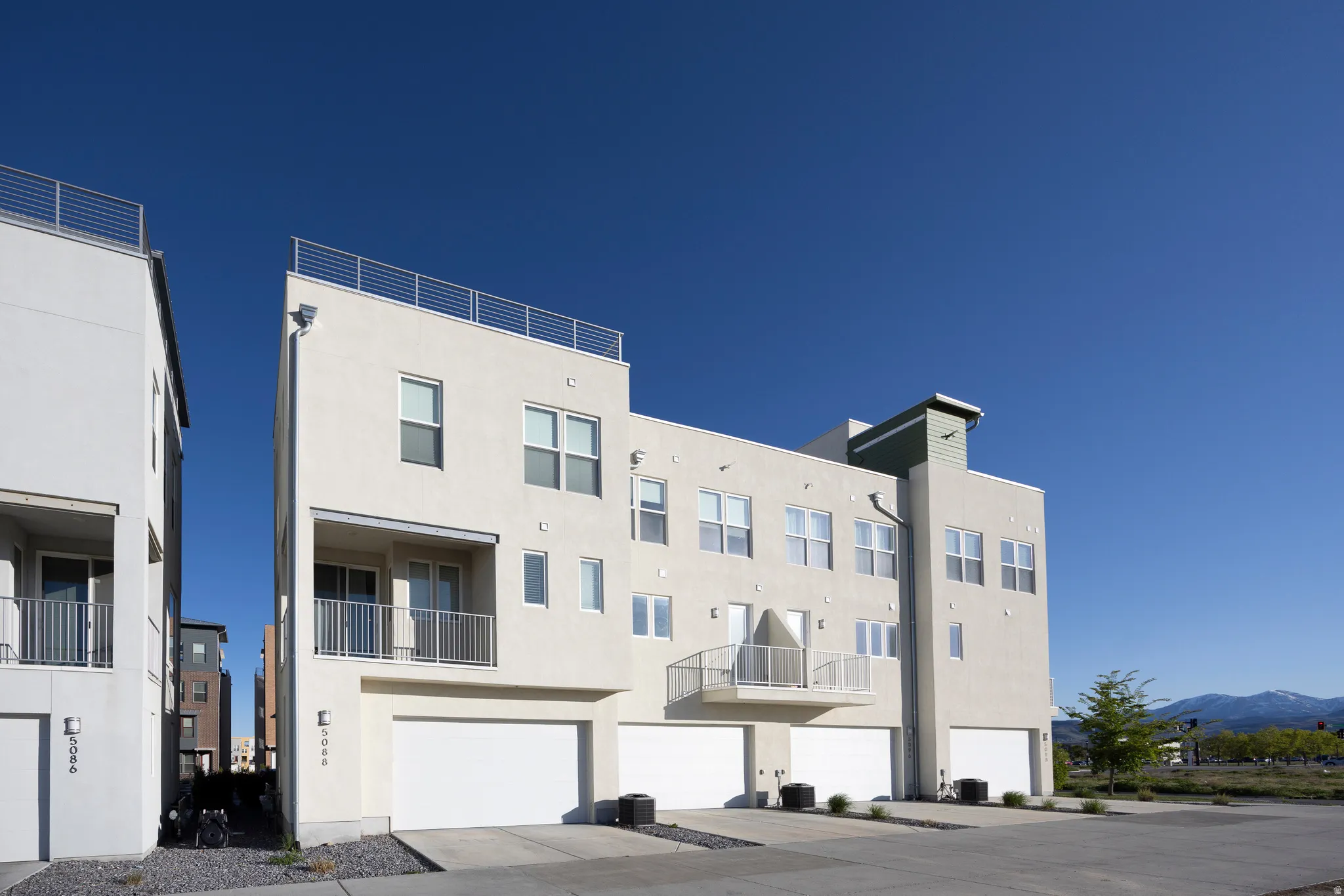 Modern multi-story facade with multiple balconies and a rooftop railing system