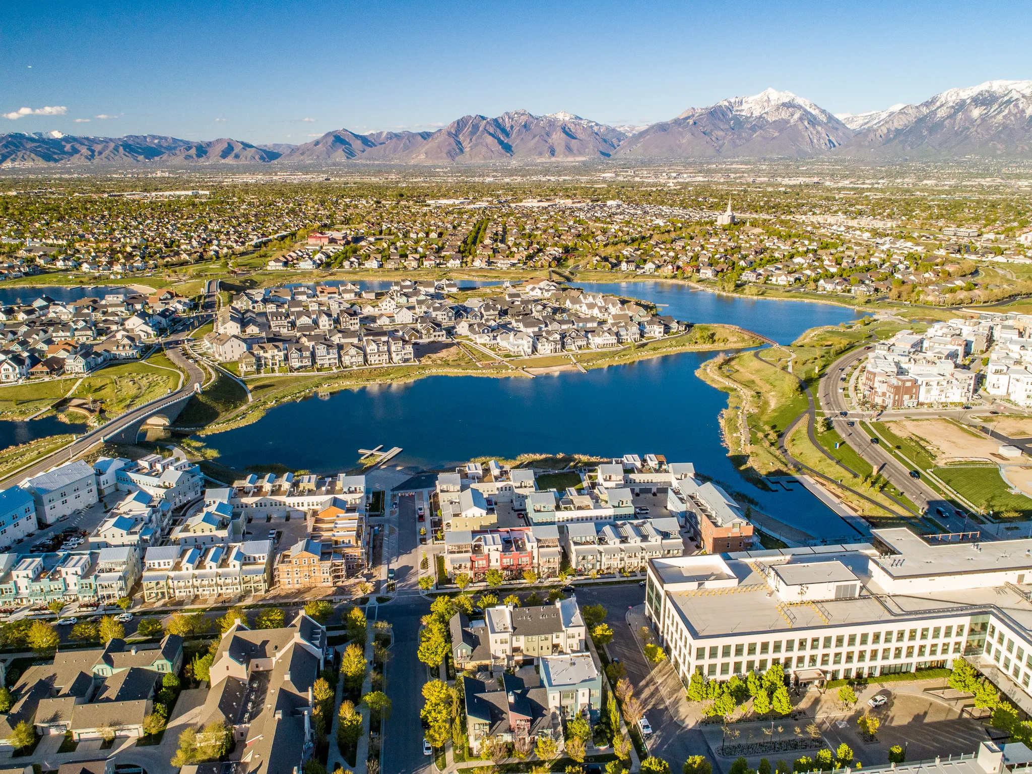 Expansive community featuring multiple bodies of water, surrounding residential properties, and distant snow-capped mountains