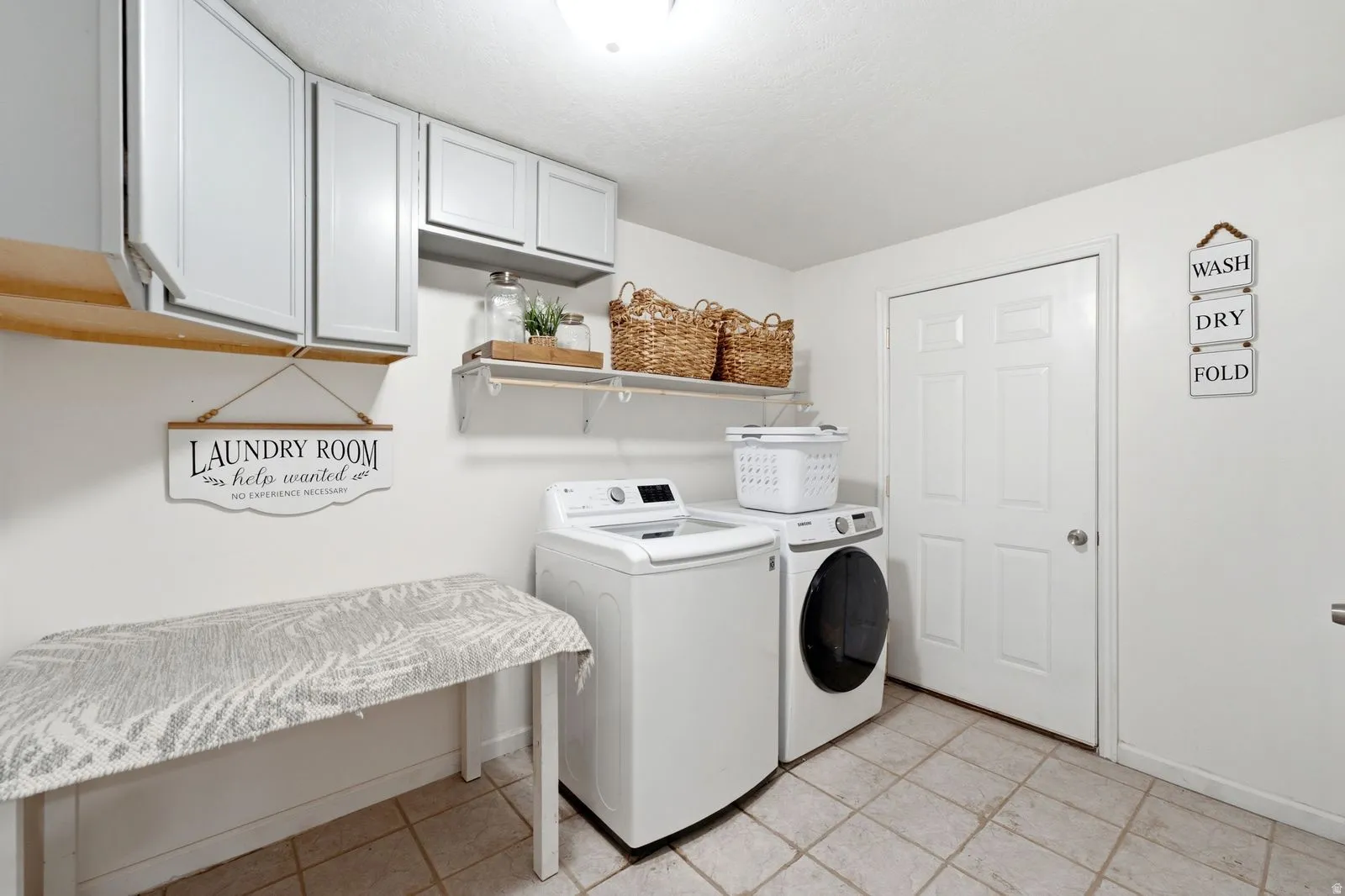 Laundry area featuring tile flooring, white shaker-style cabinetry, and a built-in shelving unit