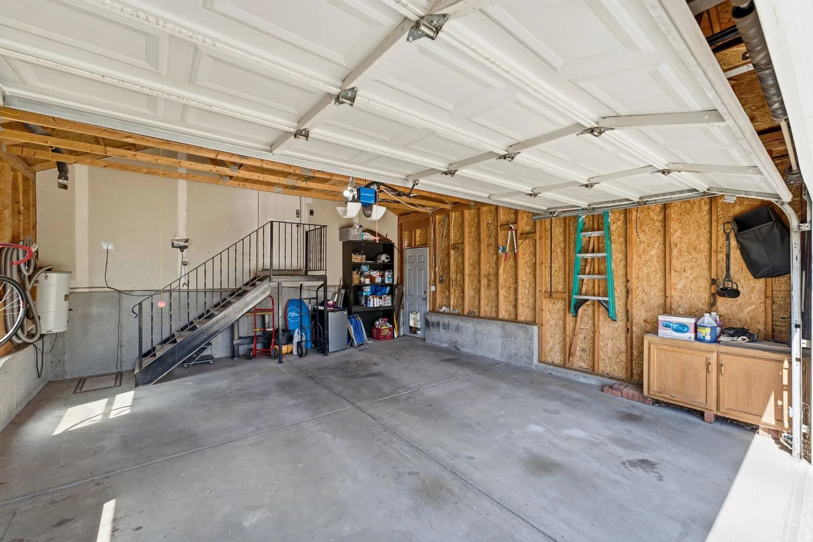 Attached garage featuring a concrete floor, built-in storage, and an interior stairway