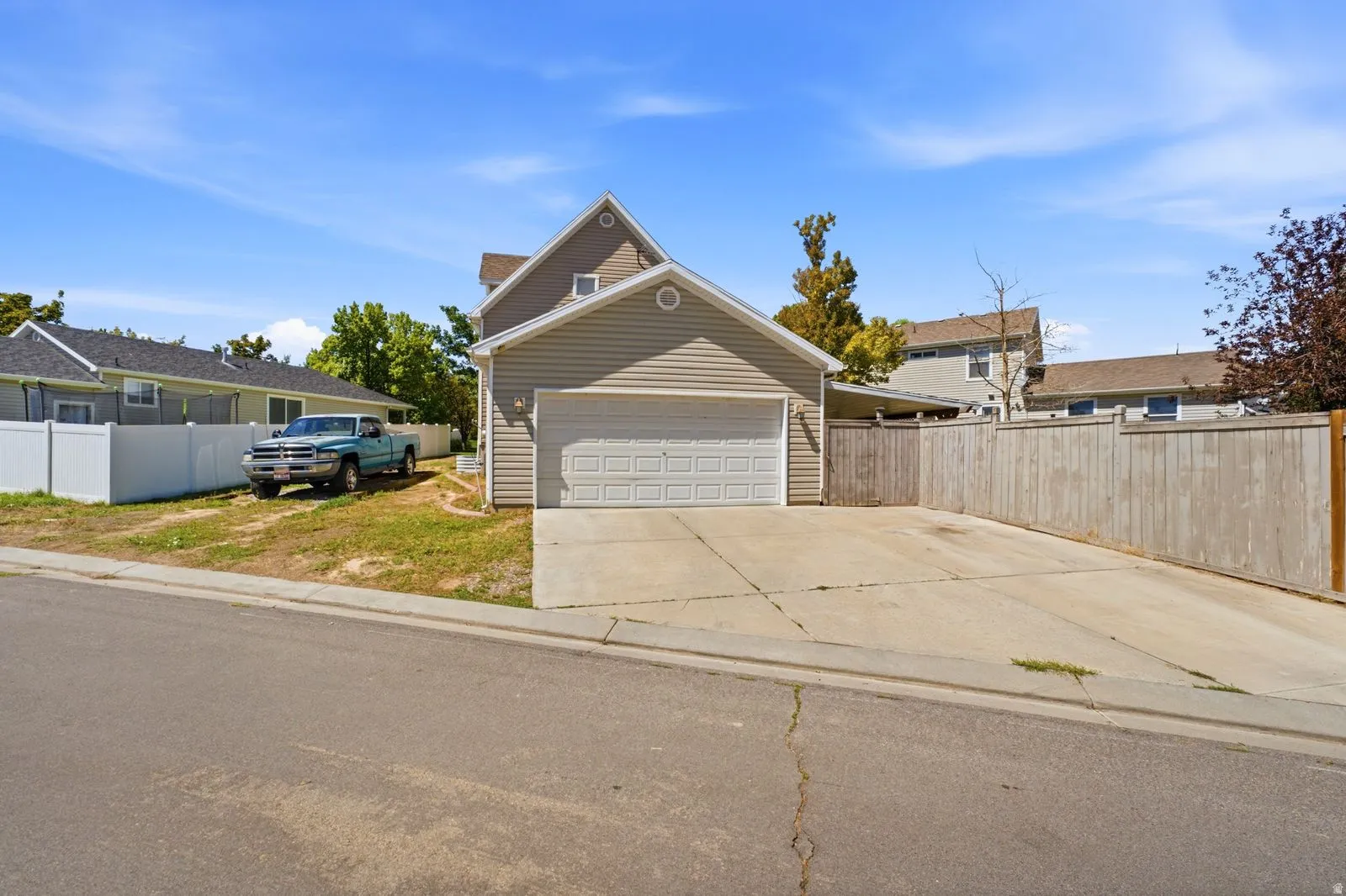 Attached two-car garage with a panel door, concrete driveway, and vertical wood fencing
