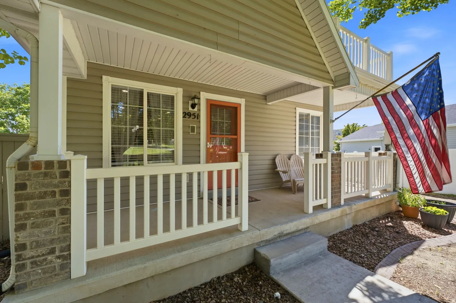 Covered front porch with white railings and brick accents