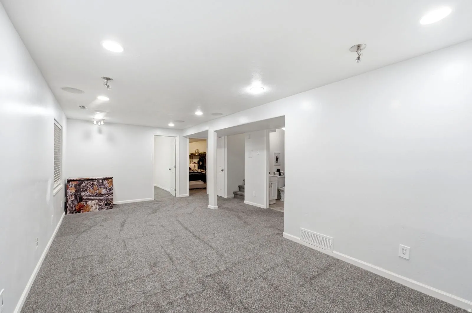 Spacious room featuring neutral carpeting, recessed ceiling lighting, and multiple doorways