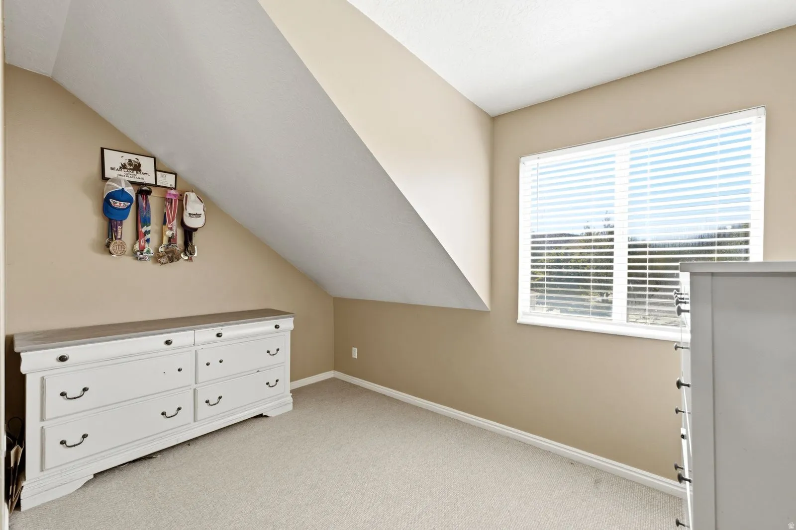 Recessed window with white blinds, neutral wall paint, and sloped ceiling