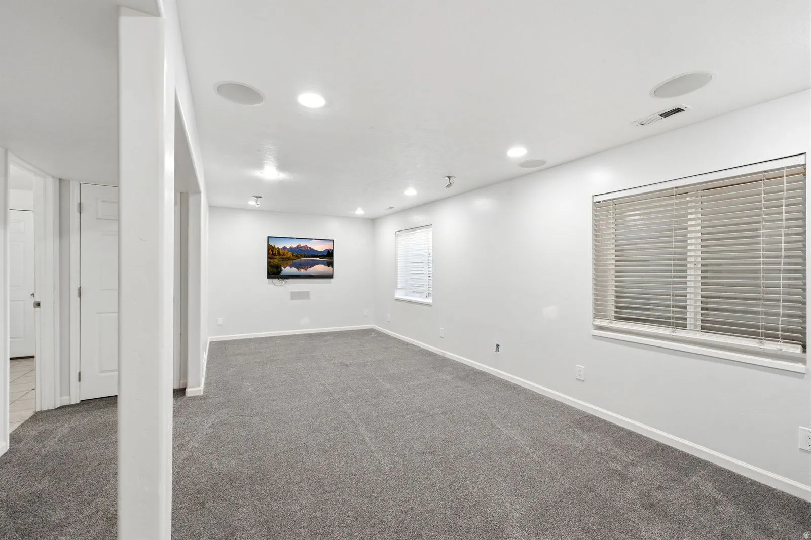 Neutral color palette with recessed lighting, integrated ceiling speakers, and carpet flooring