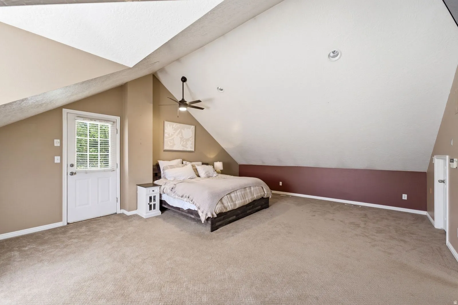 Vaulted ceiling with an integrated ceiling fan and recessed lighting, plush carpet flooring, and a glass-paned exterior door