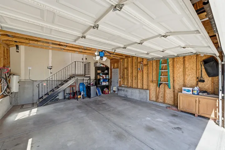Attached garage featuring a concrete floor, built-in storage, and an interior stairway
