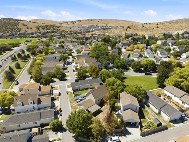 Residential neighborhood with a green space, mature trees, and mountainous backdrop