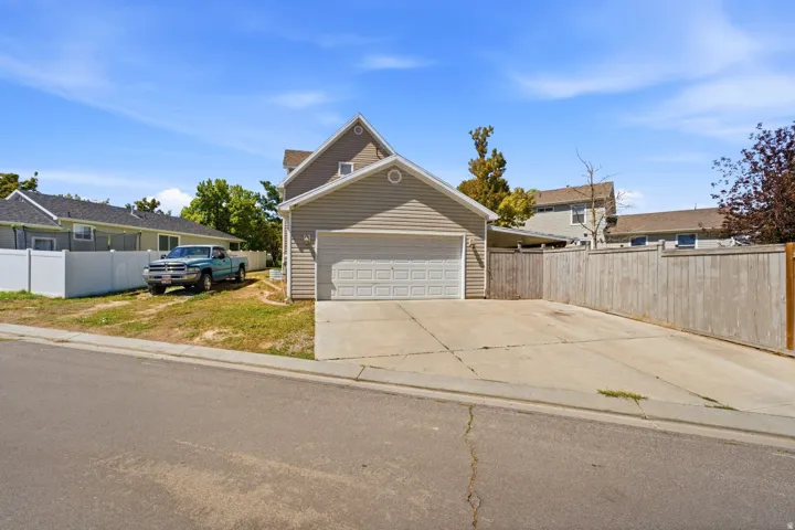 Attached two-car garage with a panel door, concrete driveway, and vertical wood fencing