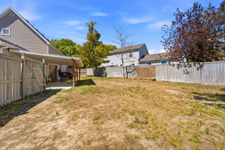 Expansive yard with wood fencing and a covered concrete patio