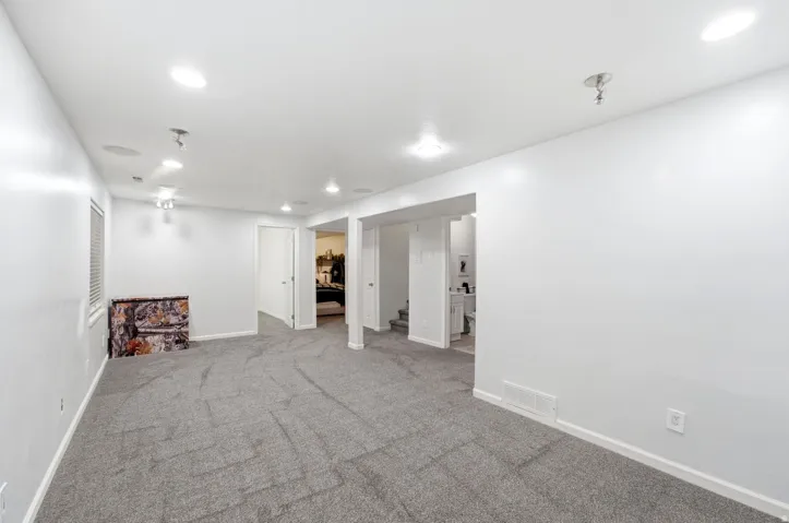 Spacious room featuring neutral carpeting, recessed ceiling lighting, and multiple doorways