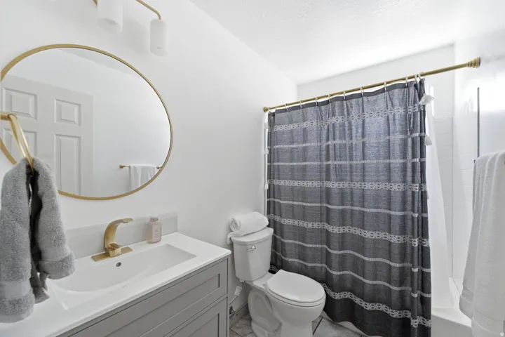 Vanity with a single basin, gold-finish faucet, and round mirror