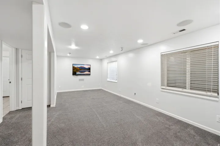 Neutral color palette with recessed lighting, integrated ceiling speakers, and carpet flooring