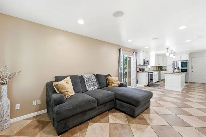 Open-concept living area featuring a kitchen with white cabinetry, stainless steel appliances, a center island with pendant lighting, and checkered tile flooring