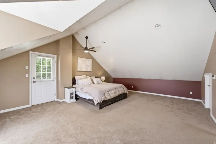 Vaulted ceiling with an integrated ceiling fan and recessed lighting, plush carpet flooring, and a glass-paned exterior door