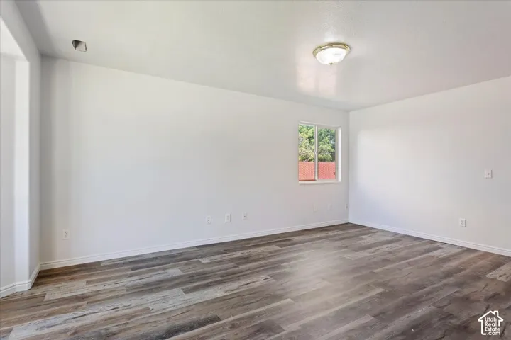 Wood-finish flooring, white walls, and a flush mount ceiling light