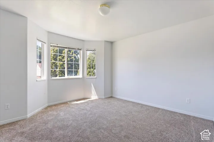 Bay window with multiple paneled windows, wall-to-wall carpeting, white painted walls, and a ceiling-mounted light fixture