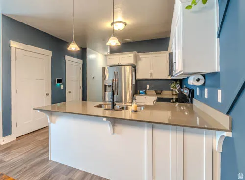 Modern kitchen featuring white shaker-style cabinetry, stainless steel appliances, and a quartz countertop island with waterfall edge