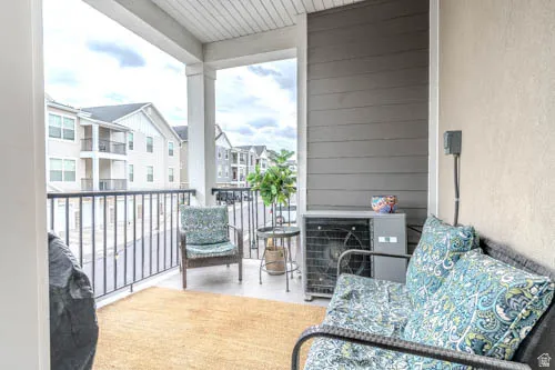Covered outdoor balcony featuring white columns, a dark metal railing, and horizontal siding