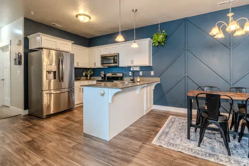 Kitchen featuring white cabinetry, stainless steel appliances, a center island with pendant lighting, and wood-finish flooring
