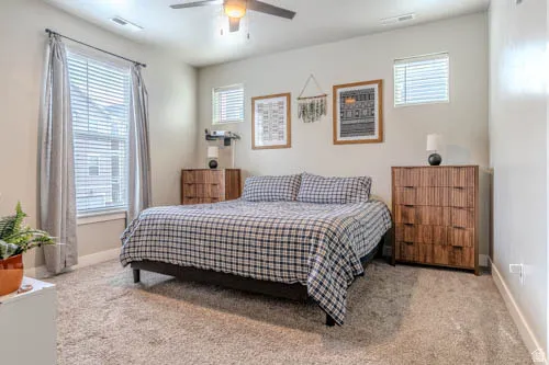 Wall-to-wall carpeting, overhead ceiling fan, and multiple windows with blinds