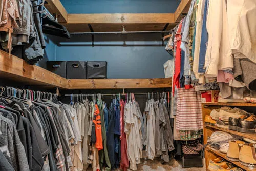 Built-in wood shelving with ample storage, integrated hanging rods, and a finished wall