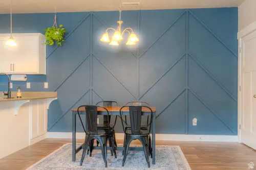 Modern dining space anchored by a geometric accent wall in soft blue with coordinating chevron paneling, hardwood flooring, and pendant lighting