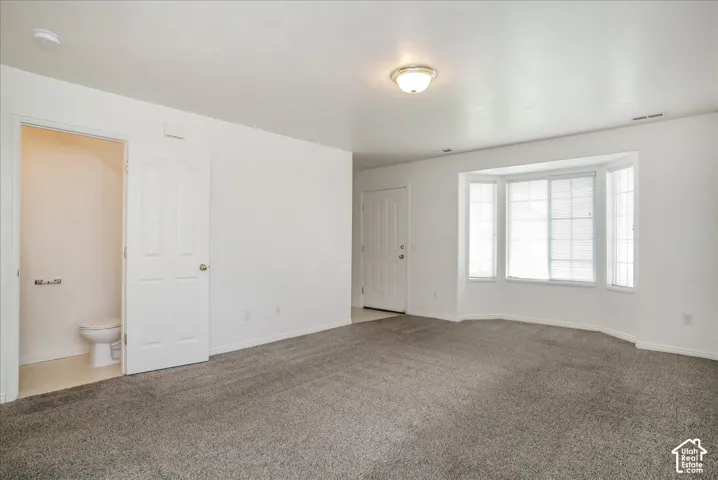 Neutral-toned carpet flooring, white walls, and a bay window with blinds