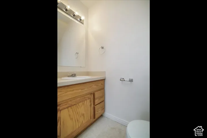 Wood-finish vanity with integrated sink, chrome faucet, and overhead vanity lighting