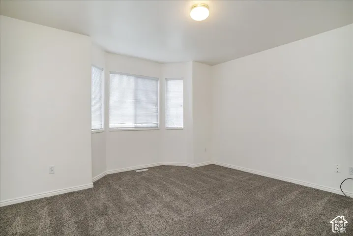 Recessed bay window design with multiple windows, neutral wall paint, gray carpeting, and an overhead flush-mount light fixture