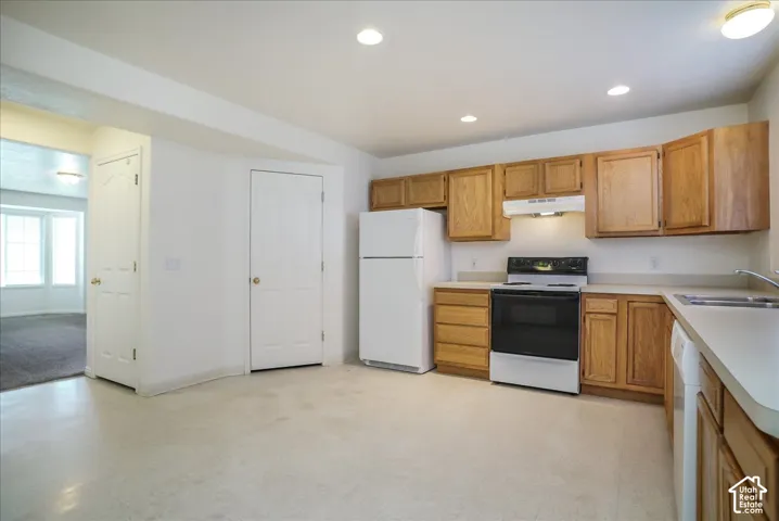 Kitchen featuring light wood-finish cabinetry, white appliances, and light-toned countertops