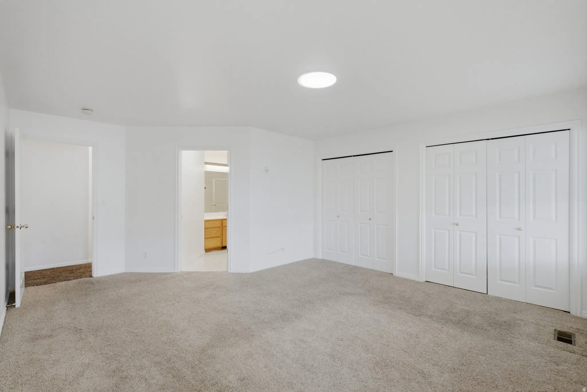 Carpeted room featuring multiple bi-fold closet doors and a ceiling skylight