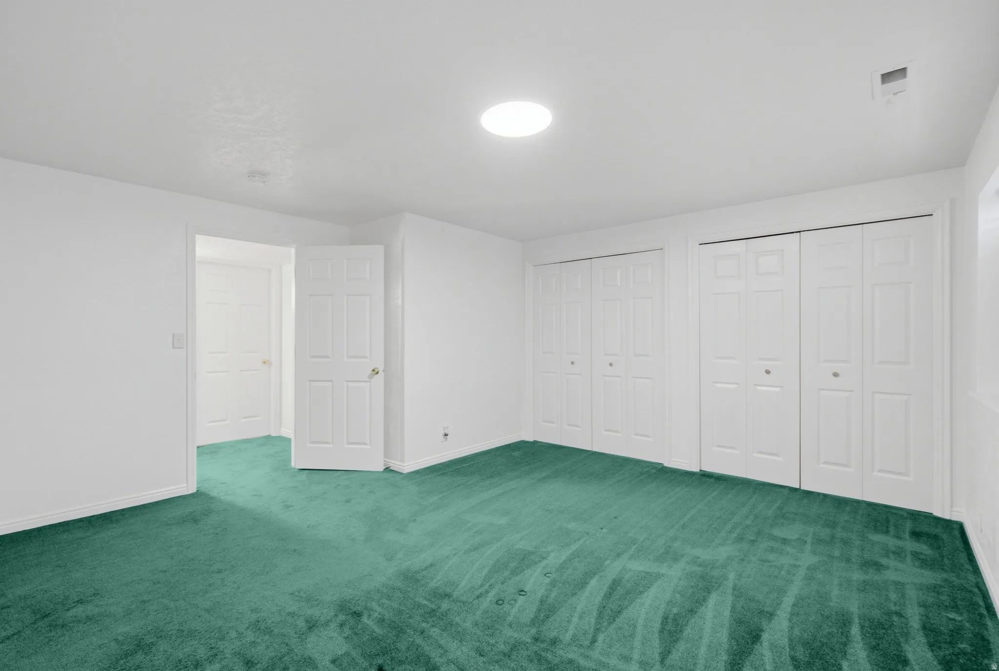 Green carpeting, white walls, and bright overhead lighting